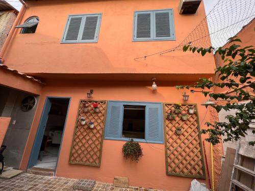 an orange building with blue shutters and a window at Hostel El Caminito LGBTQIAPN plus in Santos