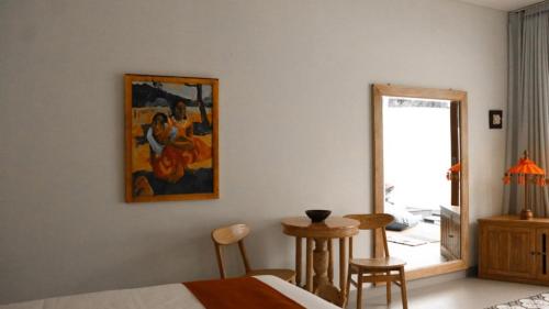 a bedroom with a table and a painting on the wall at The Seaglass Villas Bingin in Uluwatu