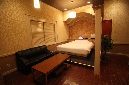 a room with a bed and a couch and a table at Utovilla HOTEL555 沼津店 in Numazu