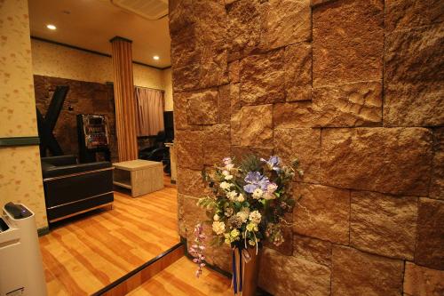 a lobby with a stone wall with a vase of flowers at Utovilla HOTEL555 沼津店 in Numazu