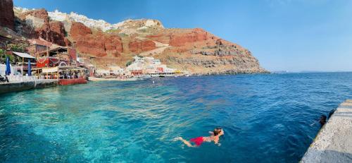a person swimming in the water near a beach at Arcana Santorini Villas, An Authentic Cycladic Experience in Akrotiri