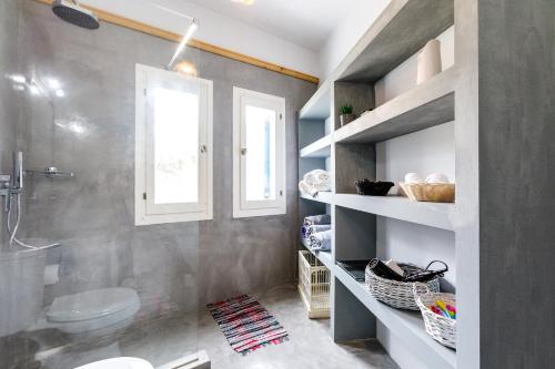 uma casa de banho com um lavatório, um WC e uma janela. em Arcana Santorini Villas, An Authentic Cycladic Experience em Acrotíri