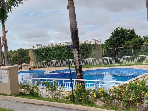 a swimming pool with a palm tree next to a fence at APARTAMENTO ACONCHEGANTE PROXIMO A PRAIA DO ARACAGY in São Luís