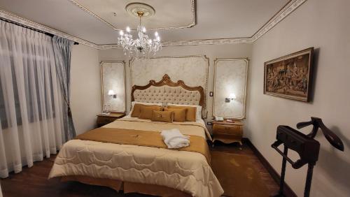 a bedroom with a large bed and a chandelier at San Juan Hotel in Cuenca