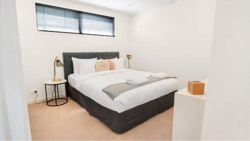 een slaapkamer met een groot bed met witte lakens bij Whakatipu Bliss in Queenstown