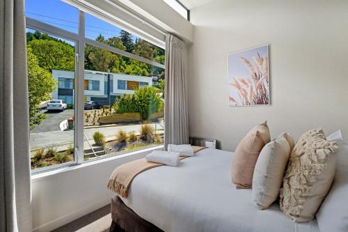 a bedroom with a bed and a large window at Tahuna Views in Queenstown