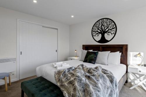 a bedroom with a bed with a tree on the wall at Bluewater Views in Queenstown