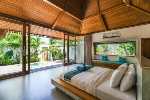una camera da letto con un letto grande in una stanza con finestre di Molokai Suites a Uluwatu