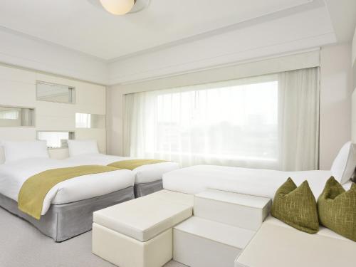 a white bedroom with two beds and a couch at Urayasu Brighton Hotel Tokyo Bay in Urayasu