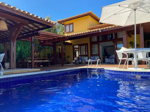 a house with a swimming pool and an umbrella at Costa do Sauipe Casa dentro do complexo hoteleiro in Costa do Sauipe
