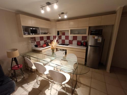 a kitchen with a glass table and white chairs at Laguna Vista Algarrobo in Algarrobo