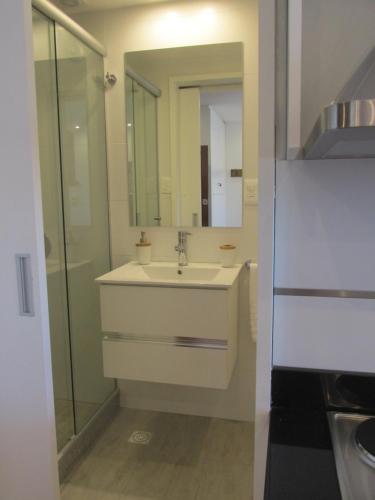 Baño blanco con lavabo y espejo en Apartamento en el palacio salvo candombe, en Montevideo