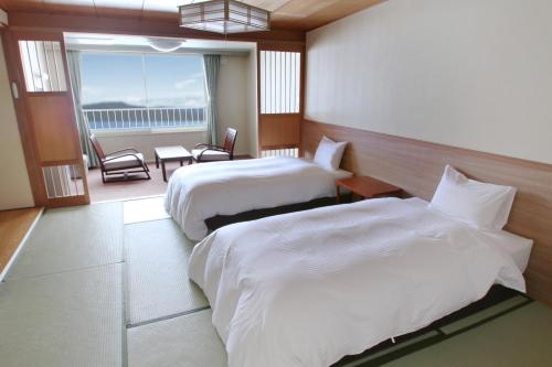 a hotel room with two beds and a balcony at Hotel Gozensui in Akankohan