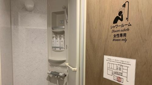Hostel Marika -ホステルマリカ- في نيتشينان: باب فيه لافته في الحمام مع مكينه