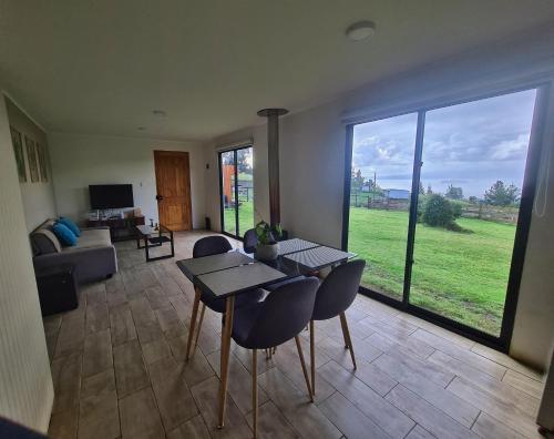 uma sala de estar com uma mesa e cadeiras e uma grande janela em Cabaña Puro Ranco em Lago Ranco