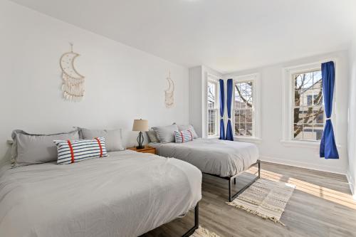 two beds in a white room with blue curtains at Orange Oasis in the Heart of East Rock with FREE parking near DT and Yale in New Haven