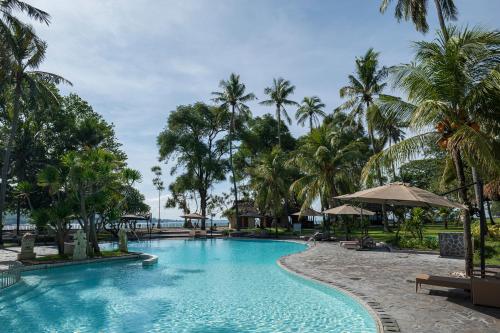 a pool at a resort with palm trees at Merumatta Senggigi Lombok in Senggigi 