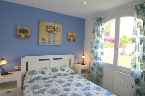 a blue bedroom with a bed and a window at ARENDA Pino Alto Villa Gallo in Miami Platja