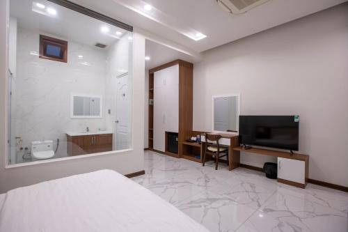 a bedroom with a bed and a tv and a bathroom at Hoang Hung Hotel in Dĩ An