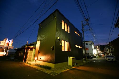a green building with windows on a street at night at PrimeRoom別府 Root in Beppu