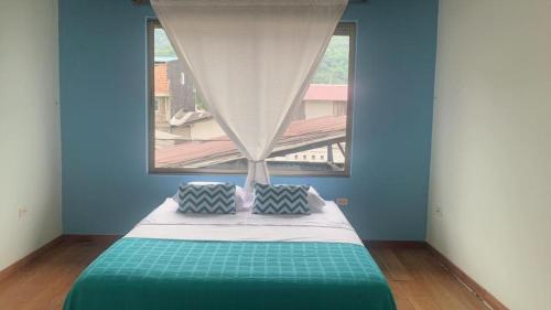 a blue room with a bed with a window at Aloja-T en Casa de Playa Bahia Solano in Bahía Solano