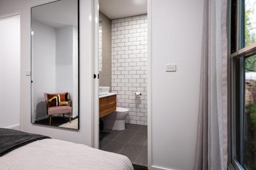 a bathroom with a toilet and a sink and a mirror at Vue Lake Daylesford Studio in Daylesford