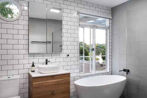 ein Badezimmer mit einer Badewanne, einem Waschbecken und einem Spiegel in der Unterkunft Vue Lake Daylesford Villa in Daylesford