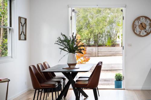 a dining room with a table and chairs and a clock at Vue Lake Daylesford Villa- lakeside luxury in Daylesford