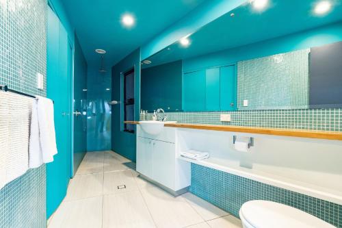 een badkamer met blauwe muren, een toilet en een wastafel bij Laaqua in Blueys Beach