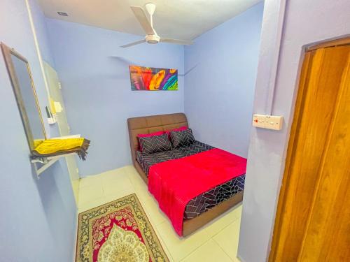 a small room with a bed with a red blanket at Nail Homestay Kuala Besut in Kuala Besut