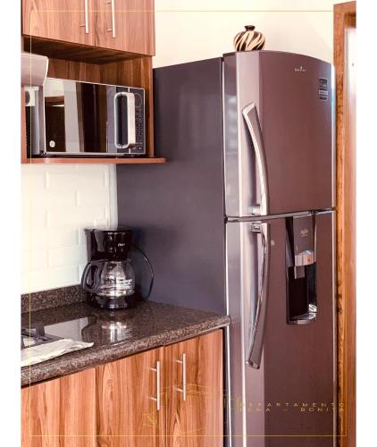 a kitchen with a stainless steel refrigerator and wooden cabinets at Departamento Loma-Bonita in Guadalajara