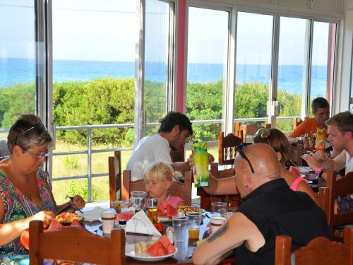 een groep mensen die in een restaurant eten bij Pink Palace Beach Resort in Agios Gordios