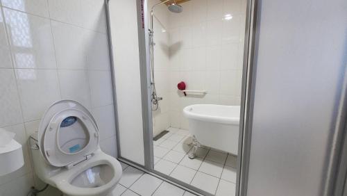 a white bathroom with a toilet and a sink at Clare Holiday B&B in Checheng