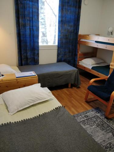 a room with two beds and a chair and a window at Gasthaus Henri in Raisio