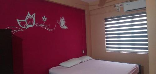 a bedroom with a red wall with a bed and a window at SAFA RESIDENCY in Perintalmanna