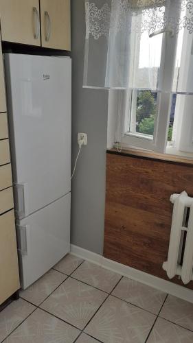 a kitchen with a white refrigerator and a window at Apartament M-3 CENTRUM in Częstochowa