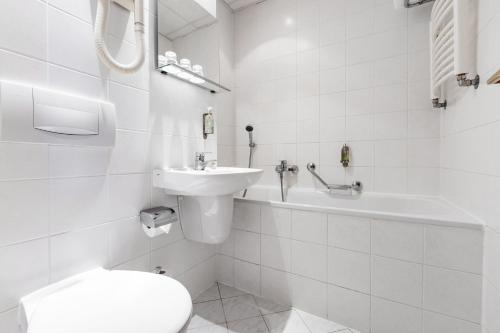 a white bathroom with a toilet and a sink at OREA Hotel Voro Brno in Brno