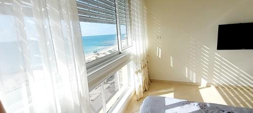 a room with a large window with a view of the ocean at Sweet Honeymoon Apartment Tel Aviv Bat Yam 611 in Bat Yam