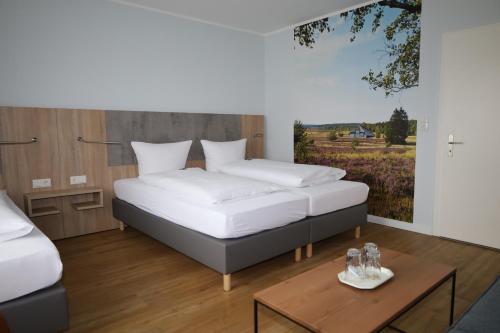 a bedroom with two beds and a table at Hotel-Pension Am Böhmepark in Soltau