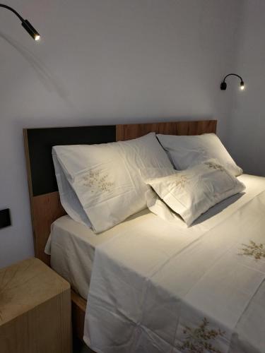 a bed with white sheets and pillows on it at Enalion residences in Tinos