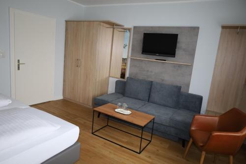 a living room with a couch and a tv at Hotel-Pension Am Böhmepark in Soltau