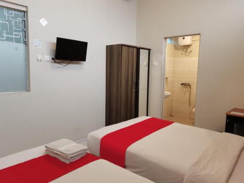 a bedroom with a bed and a television and a shower at Kozy 15 Guesthouse in Surabaya