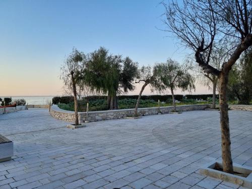 ein Park mit Bäumen und ein Ziegelweg neben dem Wasser in der Unterkunft B&b San Michele in Cagnano Varano