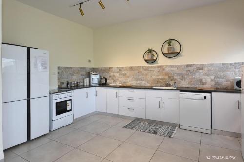 a white kitchen with white cabinets and appliances at וילה מגדלא in Migdal