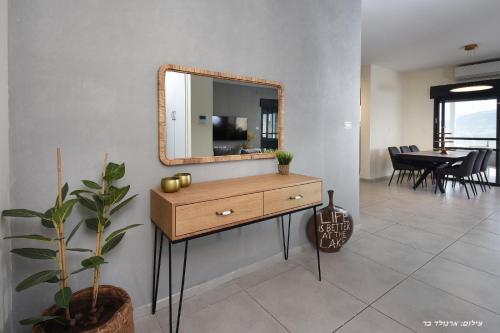 a wooden dresser with a mirror on a wall at וילה מגדלא in Migdal