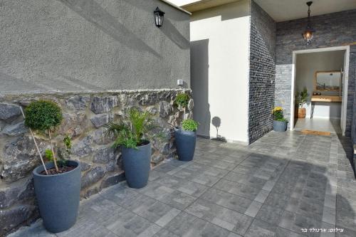 a stone wall with three potted plants on a patio at וילה מגדלא in Migdal
