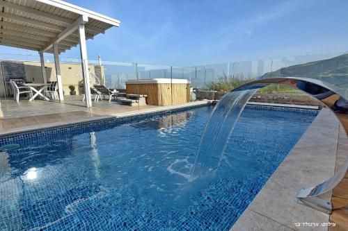 a swimming pool with a waterfall in a house at וילה מגדלא in Migdal