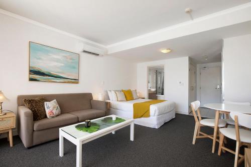 a hotel room with a bed and a couch and a table at Ettalong Beach Luxury Apartments in Ettalong Beach
