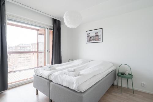 a white bedroom with a bed and a large window at 2ndhomes Tampere "Kaplan #2" Luxury Apartment - Sauna & Balcony in Tampere