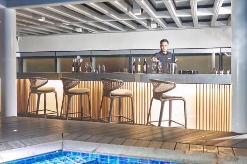 a man standing at a bar with bar stools at Kingsford Hotel Manila Bay in Manila
